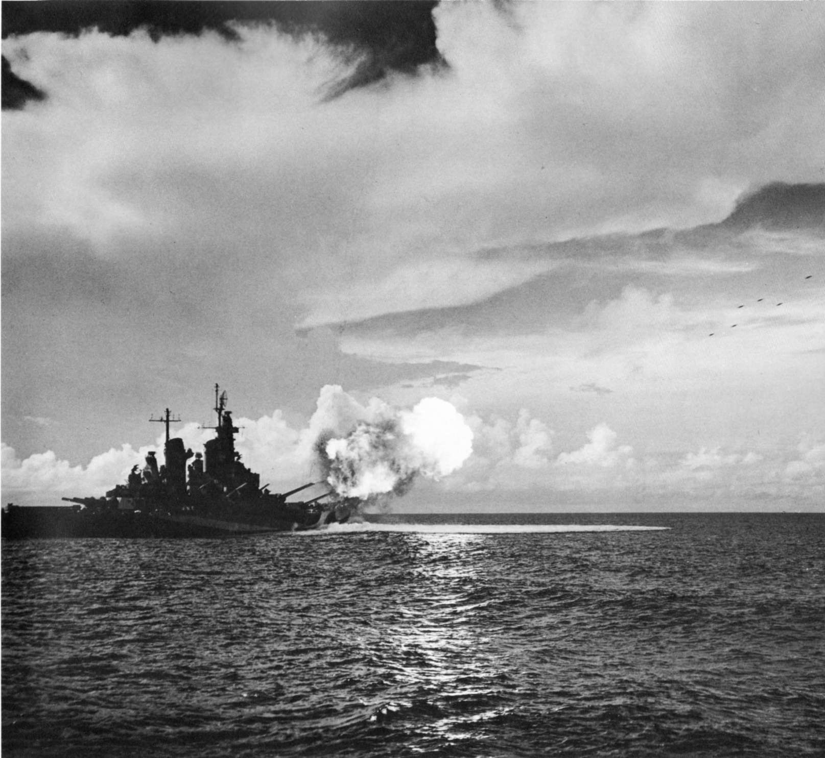 Missouri firing full salvo from both forward 16-inch gun turrets during shakedown exercise, Aug 1944; note six super-sonic projectiles at upper right; as seen on page 23 of US Navy War Photographs