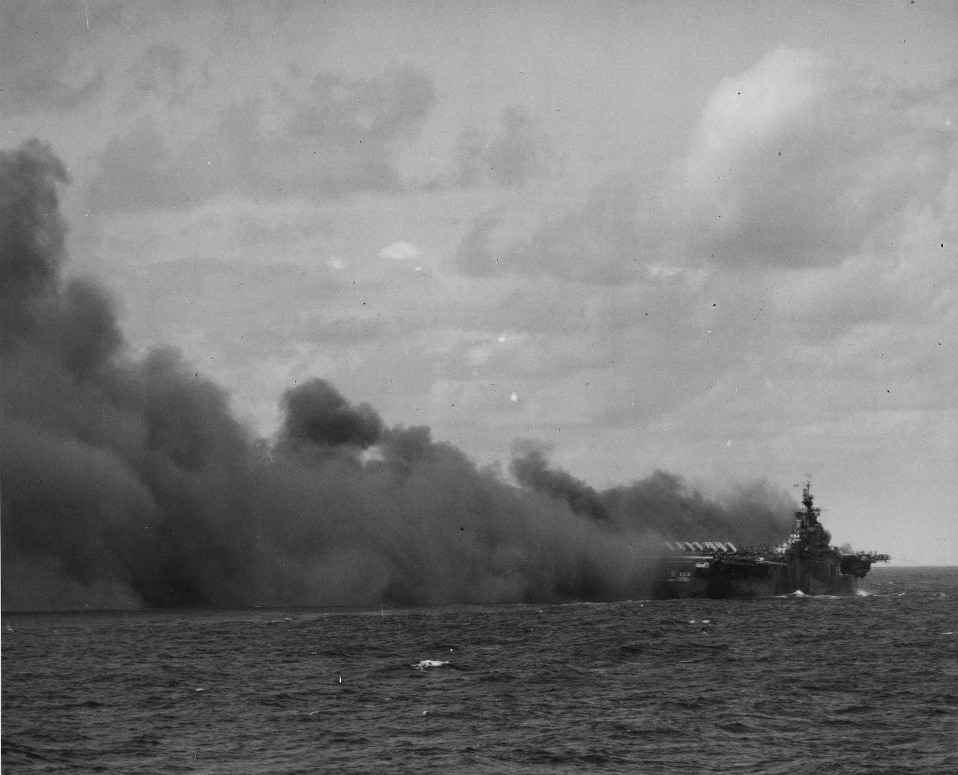 Ticonderoga shrouded in smoke after being hit by two kamikaze aircraft, 125 miles east-southeast of Taiwan, about 1300 hours on 21 Jan 1945