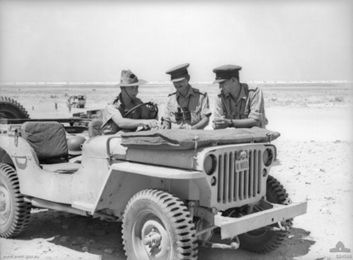 Capt TI Gellibrand and Lt JT Cook with the Australian 24th Infantry Brigade HQ, and Lt ET Pearce use the hood of a Willys MB Jeep to check a map, west of El Alamein, Egypt, 19 Jul 1942