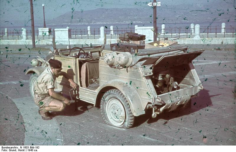 German driver operating a jack in changing a tire on a Kübelwagen in Sicily, Italy, 1943