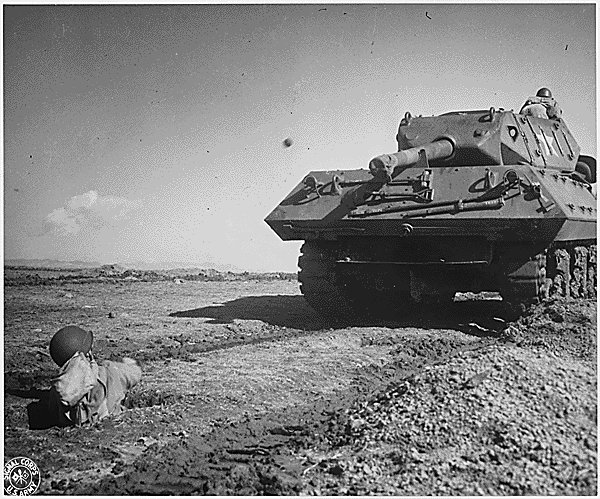 An US Army soldier practicing throwing a grenade from a foxhole toward a M10 tank destroyer, Camp Carson, Colorado, United States, 24 Apr 1943