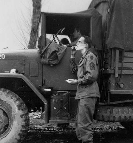 A sergeant of the US 28th Infantry Division shaving in the mirror of a M35 'deuce-and-a-half' truck, date unknown