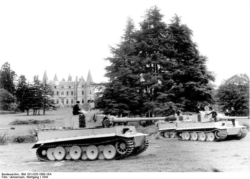 Three German Tiger I heavy tanks in a field near a castle, France, 1943