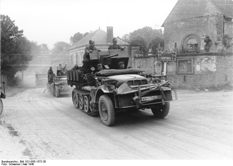 German SdKfz. 10/4 half-track vehicles with 2-cm flak guns driving through the village of Gourgançon, Marne, France, May 1940