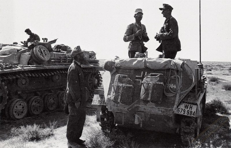 General Ulrich Kleemann of German 90th Light Africa Division speaking to a photographer aboard his SdKfz. 250 half-track command vehicle, 1942-1943; note StuG III in background