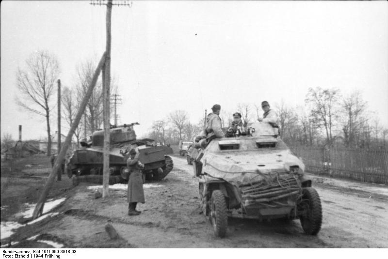 German SdKfz. 251 halftrack vehicle on a road, Russia, 21 Mar 1944, photo 1 of 2; note destroyed Russian (American-made) M4 Sherman medium tank in background