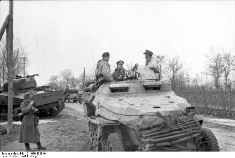 German SdKfz. 251 halftrack vehicle on a road, Russia, 21 Mar 1944, photo 2 of 2; note destroyed Russian (American-made) M4 Sherman medium tank in background