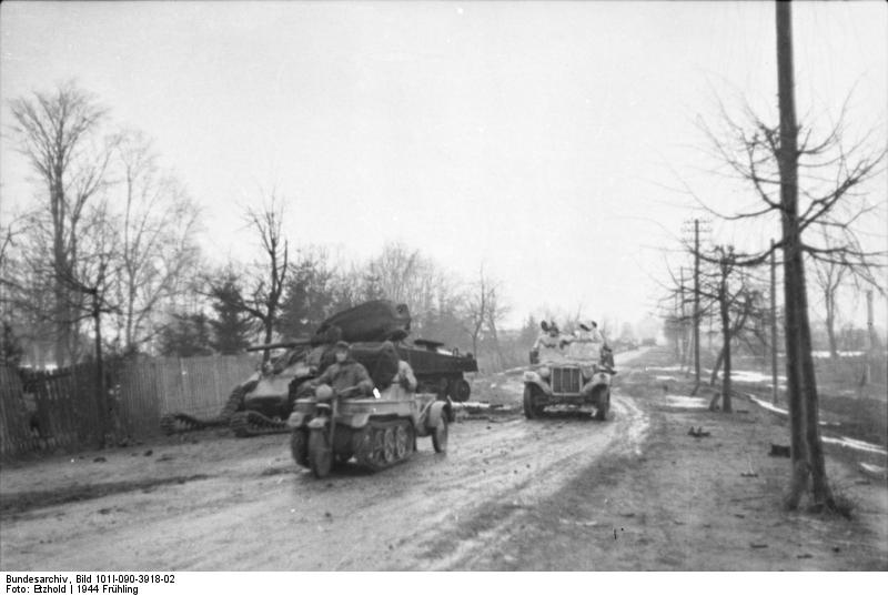 SdKfz 2 Kettenkrad and SdKfz 10 vehicles on a road in the Soviet Union, early 1944; note destroyed Sherman tank on the side of the road
