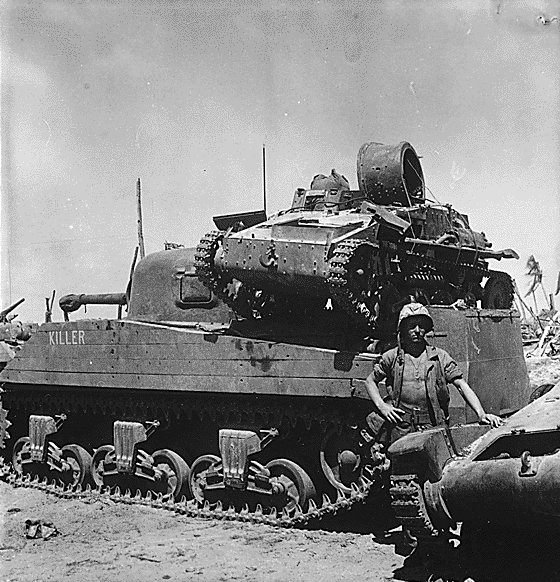 US Marine Private First Class N. E. Carling posing beside M4 Sherman tank 'Killer', which was carrying a knocked-out Japanese Type 94 Te Ke tankette, Kwajalein, Marshall Islands, 2 Feb 1944