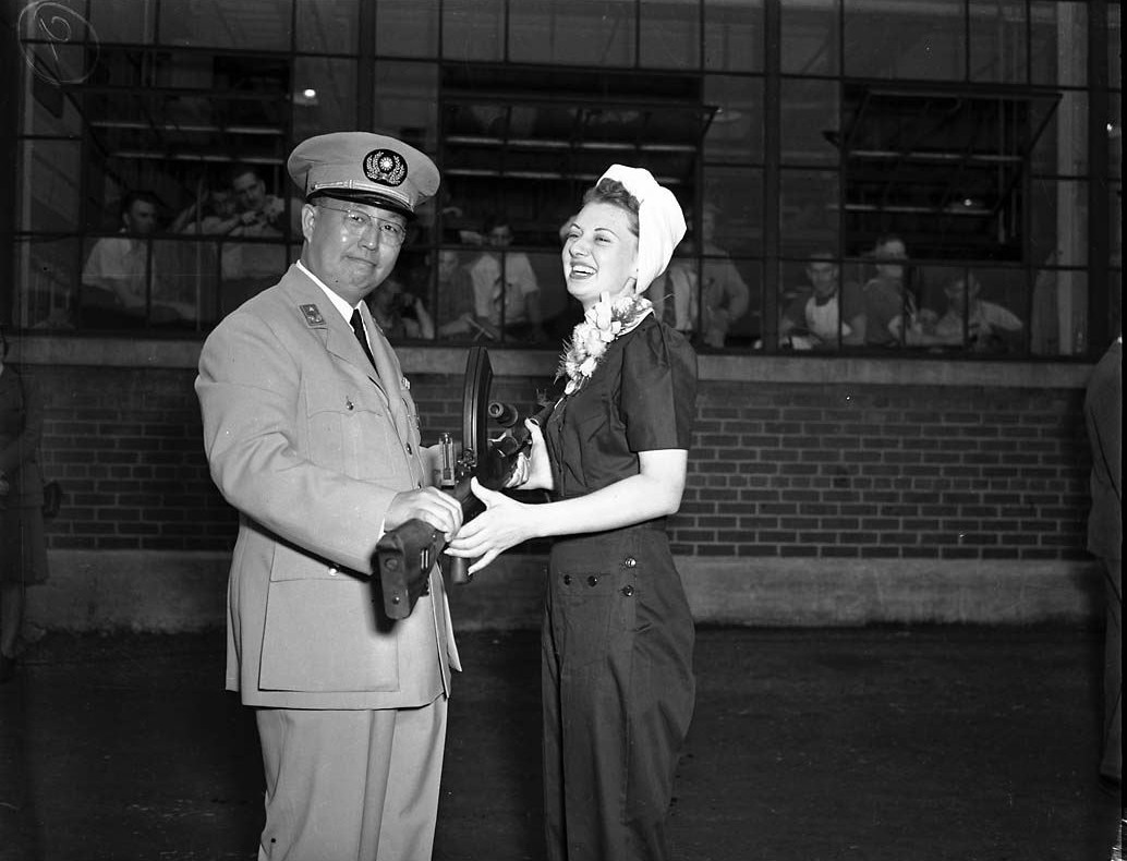 Chinese General P. Kiang and Canadian factory worker June 'Miss Inglis' Pattison with the 100,000th Bren gun built at the John Inglis and Company factory, Toronto, Canada, 20 Aug 1943