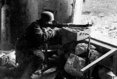 A German paratrooper defending a position with his FG 42 machine gun, Italy, circa 1944; note MP 40 submachine gun nearby