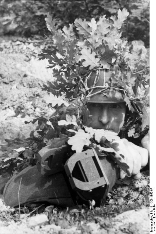 Camouflaged German soldier with 3 HL shaped charge, France, Jun 1944