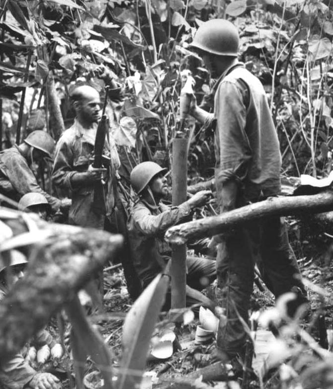 An US Marine mortar team shelling a Japanese position somewhere in the Pacific, date unknown; note the near-verticle angle of the M1 Mortar barrel and the M1 Carbine