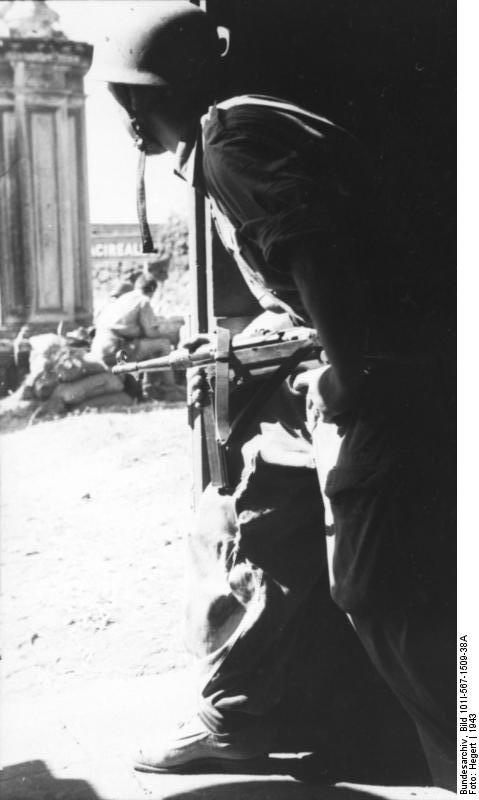 German paratrooper with MP 40 submachine gun in a doorway in Italy, 1943