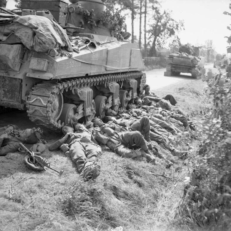 Troops of British King's Shropshire Light Infantry regiment resting next to a Sherman tank of British 3rd Royal Tank Regiment, France, 15 Aug 1944