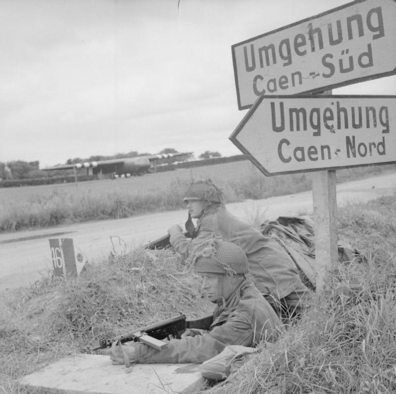 Lance Corporal A. Burton and Lance Corporal L. Barnett of British 6th Airborne Division at a road junction near Ranville, France, 7 Jun 1944; note Horsa glider in background