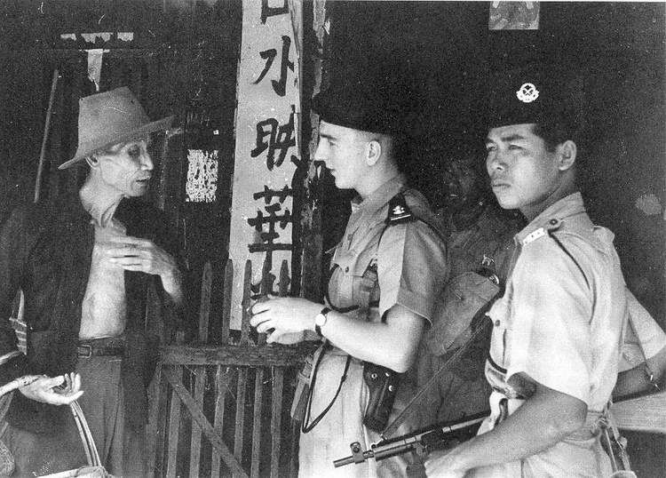 British-Malayan policemen talking to a civilian, Malaya, 23 Apr 1949; note Sten gun
