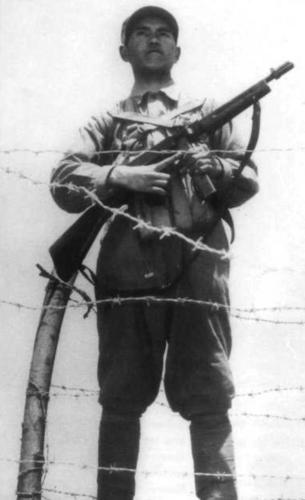 Chinese soldier standing guard with a Thompson submachine gun, date unknown